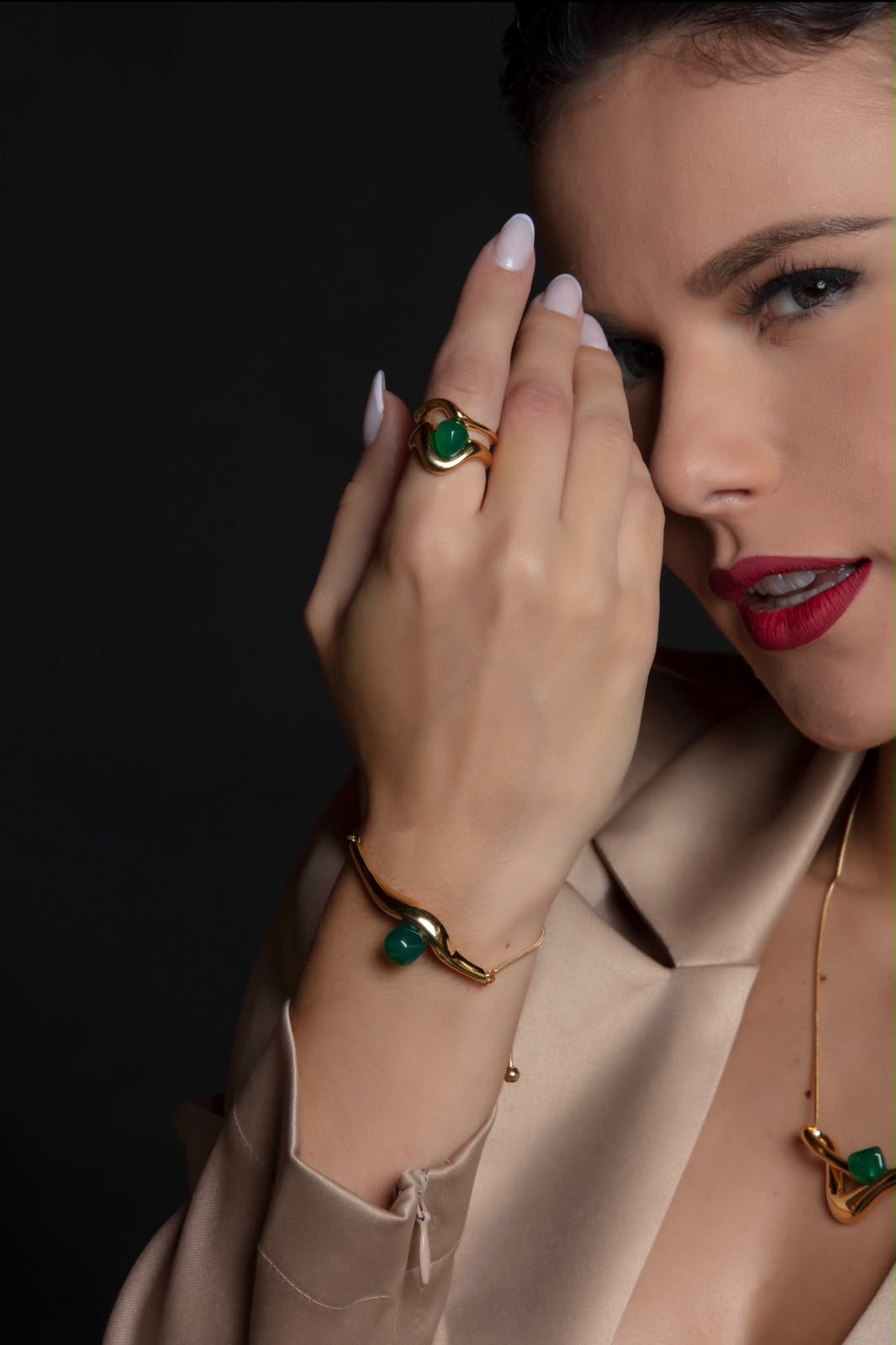 Anel dourado com pedra verde esmeralda em close-up